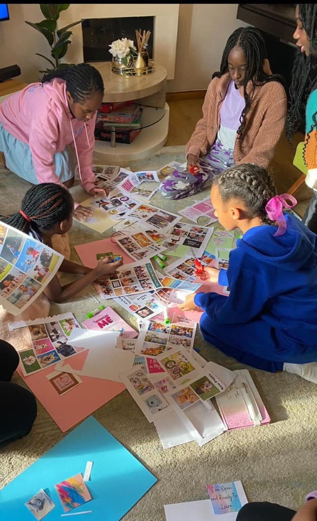 Girls and young women sitting together on the floor, cutting photos and making vision boards