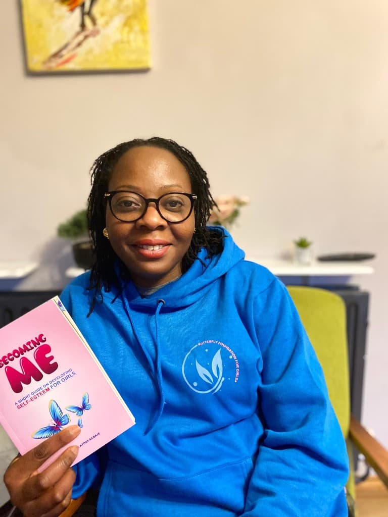 A mentor holding the Becoming Me guide on developing self-esteem for girls and young women